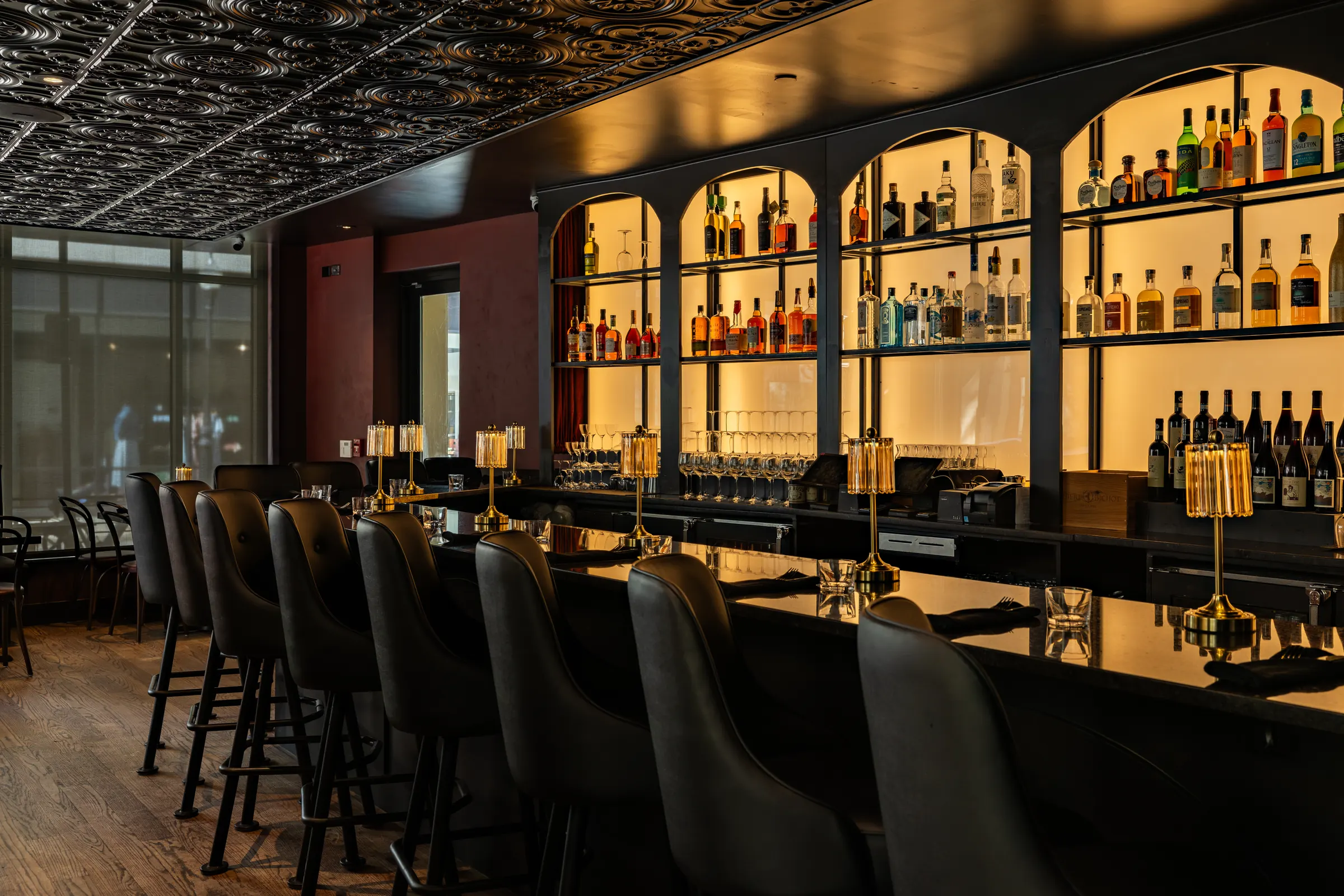 The bar at Bar Rosso, bottles on backlit arched shelves
