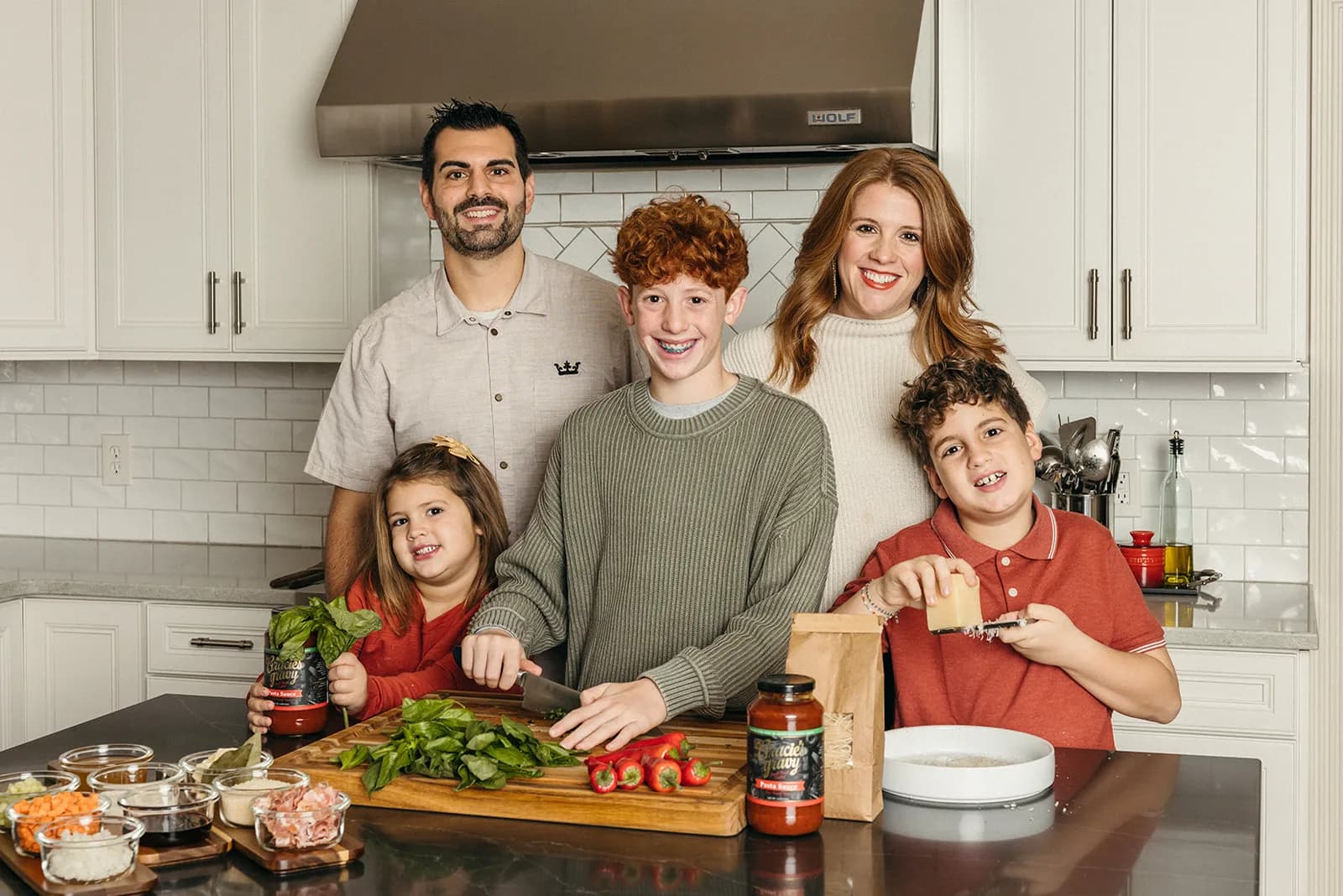 Anthony and Haley Sitek cooking with their children around the kitchen island