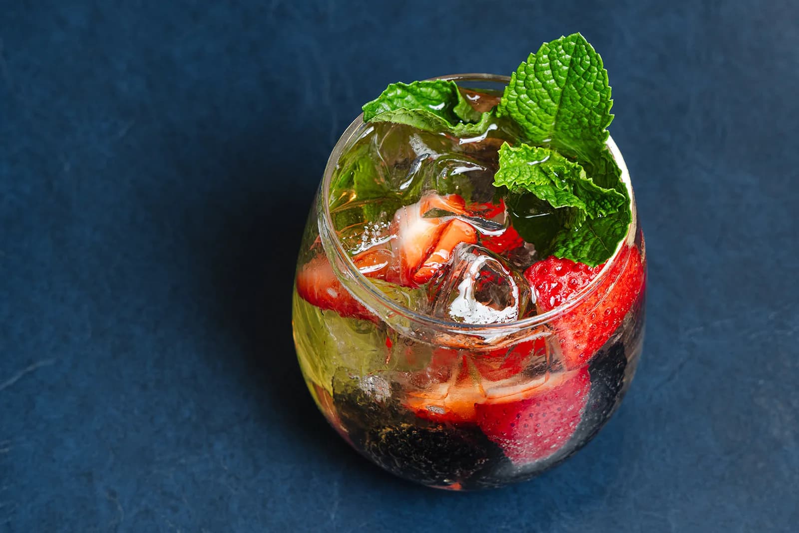 A cocktail garnished with rosemary and dried citrus on the bar