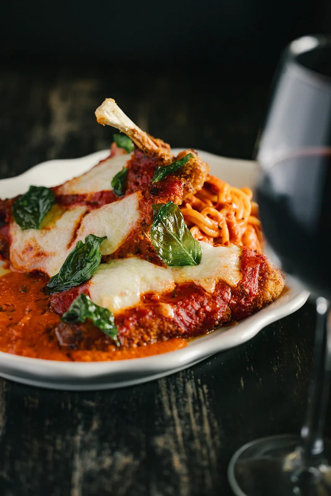 Chicken parmesan beside a glass of red wine