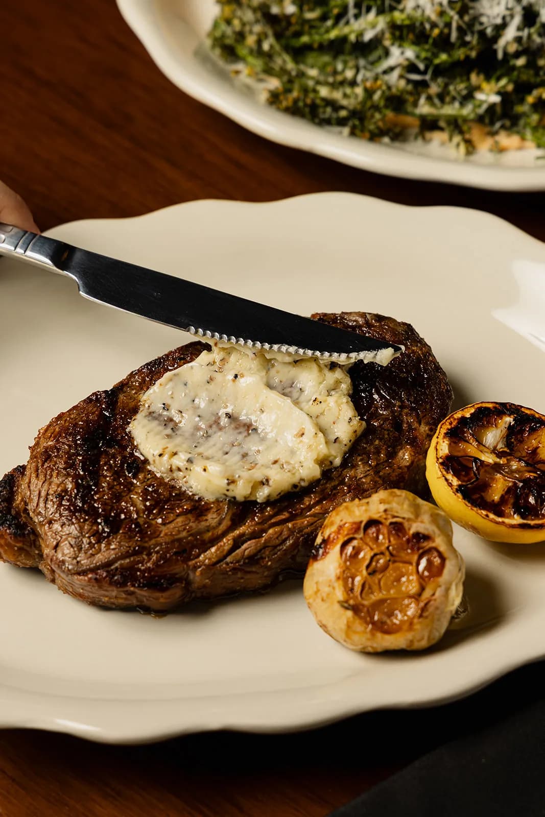 A charred ribeye finished with garlic butter and a charred lemon half