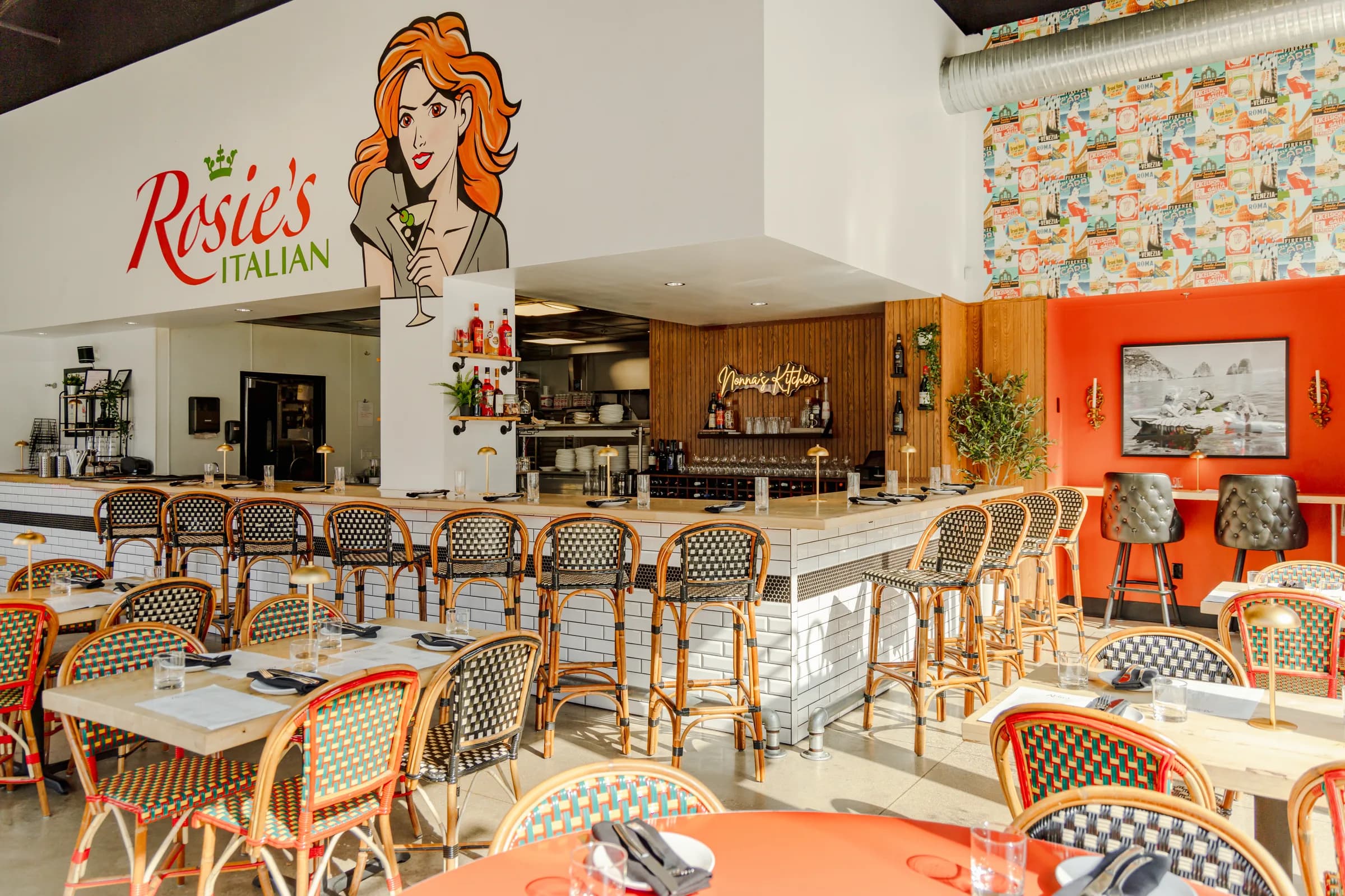 The dining room at Rosie's Italian, bistro chairs and the Rosie mural above the open kitchen